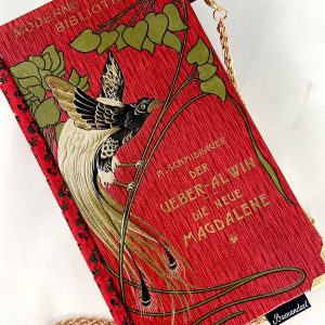 Tasche/Clutch aus einem kleinen Büchlein der Serie "Moderne Bibliothek" in rot, am Cover ein großer prächtiger Vogel, schön geprägtes Cover mit Titel "Der Über-Alvin" und " Die neue Magdalene", kombiniert mit einer roten Trachtenkrawatte passend zum Cover.
